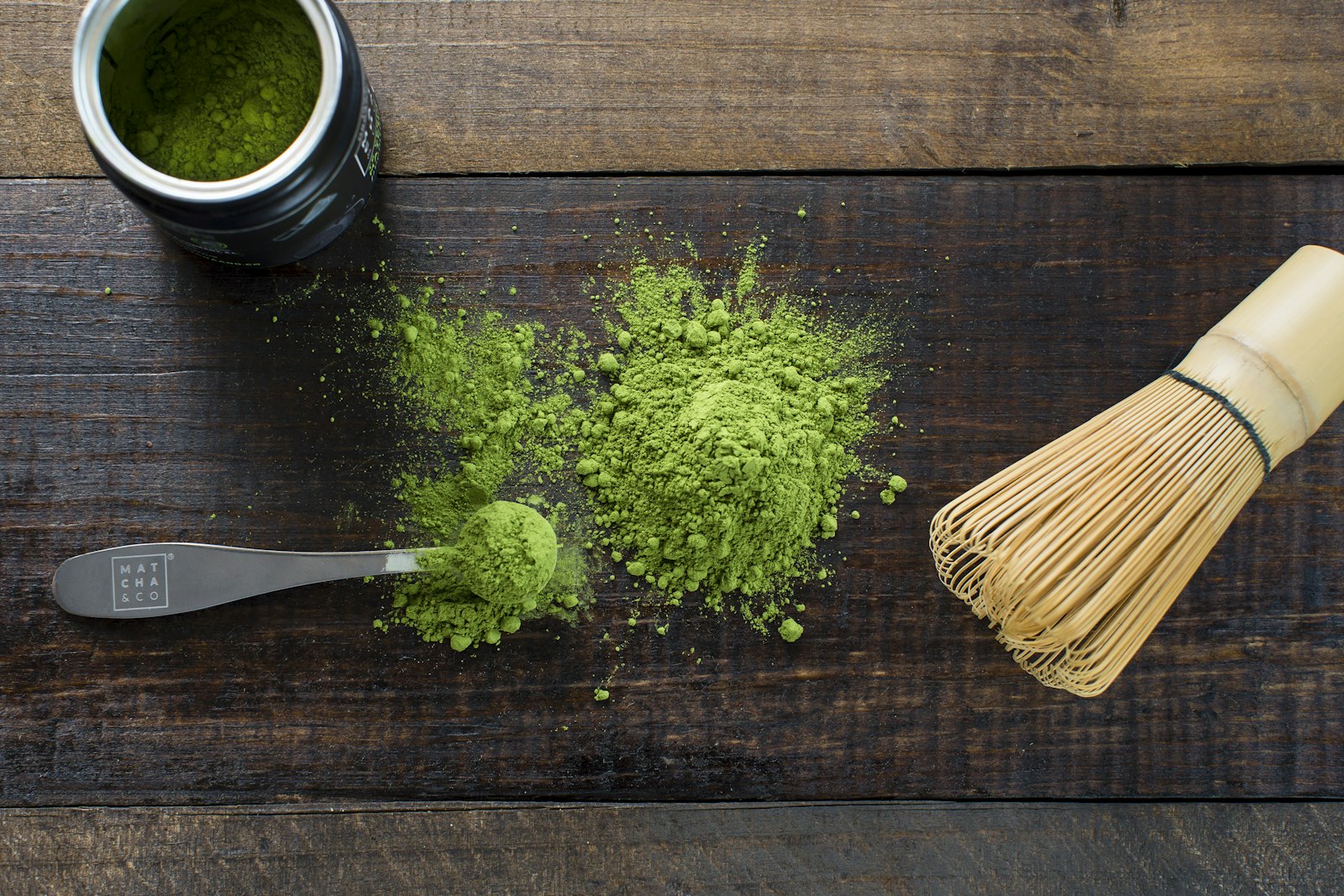Bamboo whisk, matcha powder and scoop on a wooden table